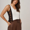 Mujer vistiendo una musculosa de escote V tejida en color blanco y chocolate para un look urbano